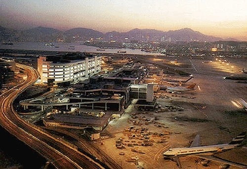 Aerial view of a cityscape with buildings, highways, and a bay at sunset.