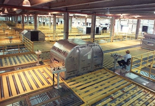A large shipping container with FedEx branding in a warehouse-like facility with yellow carts and pallets.