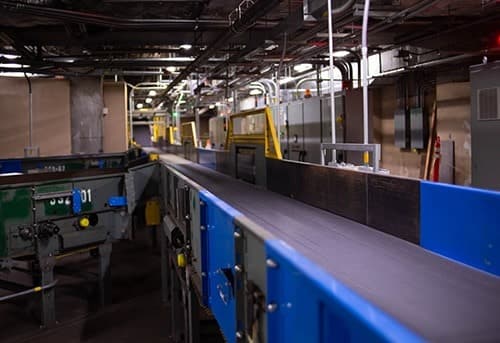 Dimly lit industrial interior with cargo containers and equipment, suggesting a warehouse or shipping facility.