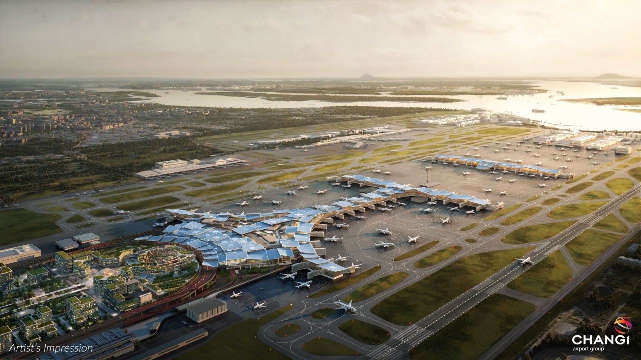 Aerial view of Changi Airport in Singapore, showcasing the expansive terminals, runways, and surrounding landscape at sunset.