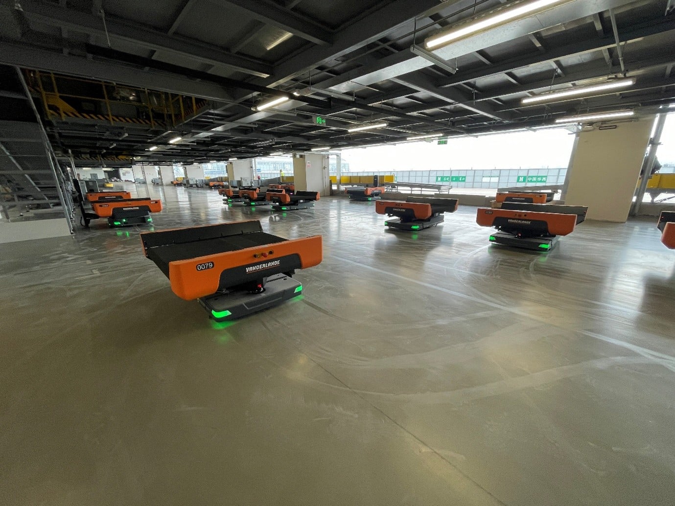 A large indoor space with numerous orange robotic platforms on the floor, suggesting an automated warehouse or logistics facility.