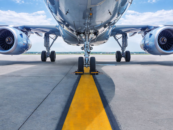 Fuselage and engines of a large commercial airplane on the tarmac, with a yellow taxi line in the foreground.
