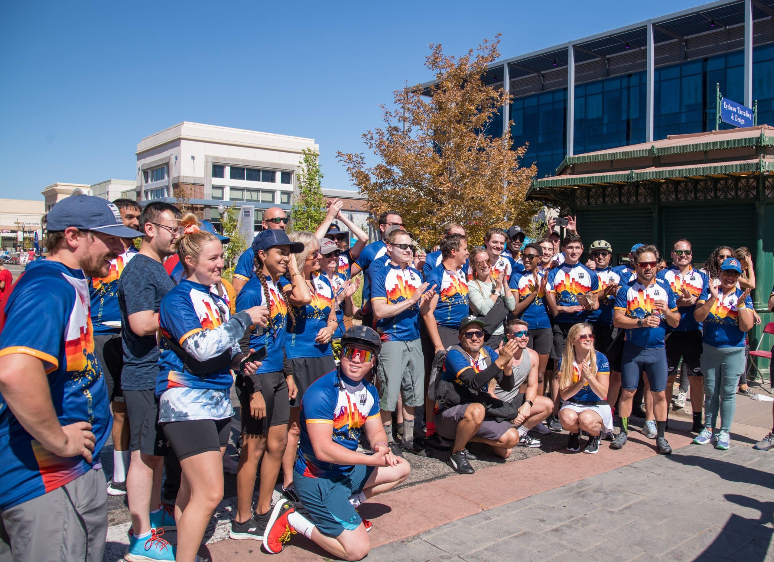 Large group of people in colorful sports uniforms gathered outdoors on a sunny day.