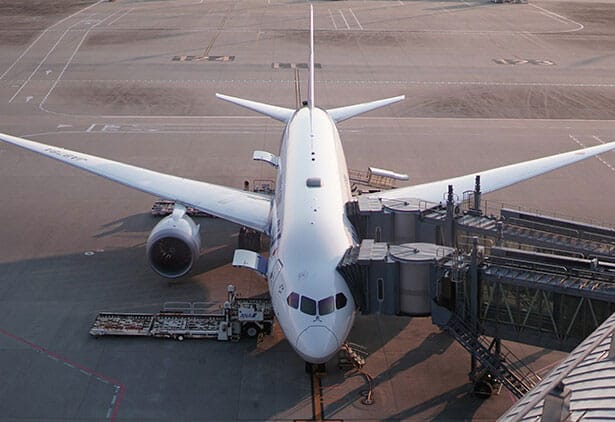 Large commercial airplane on airport tarmac with terminal infrastructure.