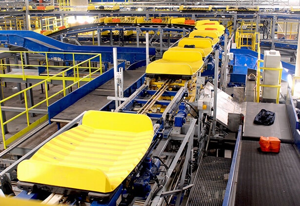 Automated baggage handling system with yellow conveyor belts and blue framing.