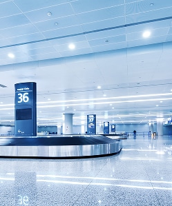 Luggage carousel in airport terminal with Gate 36 sign and bright lighting.